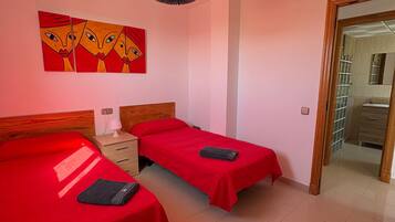 Ein Zimmer mit zwei Betten, einem Holzkopfende, einem Nachttisch mit Lampe und einem an der Wand hängenden Kunstwerk.