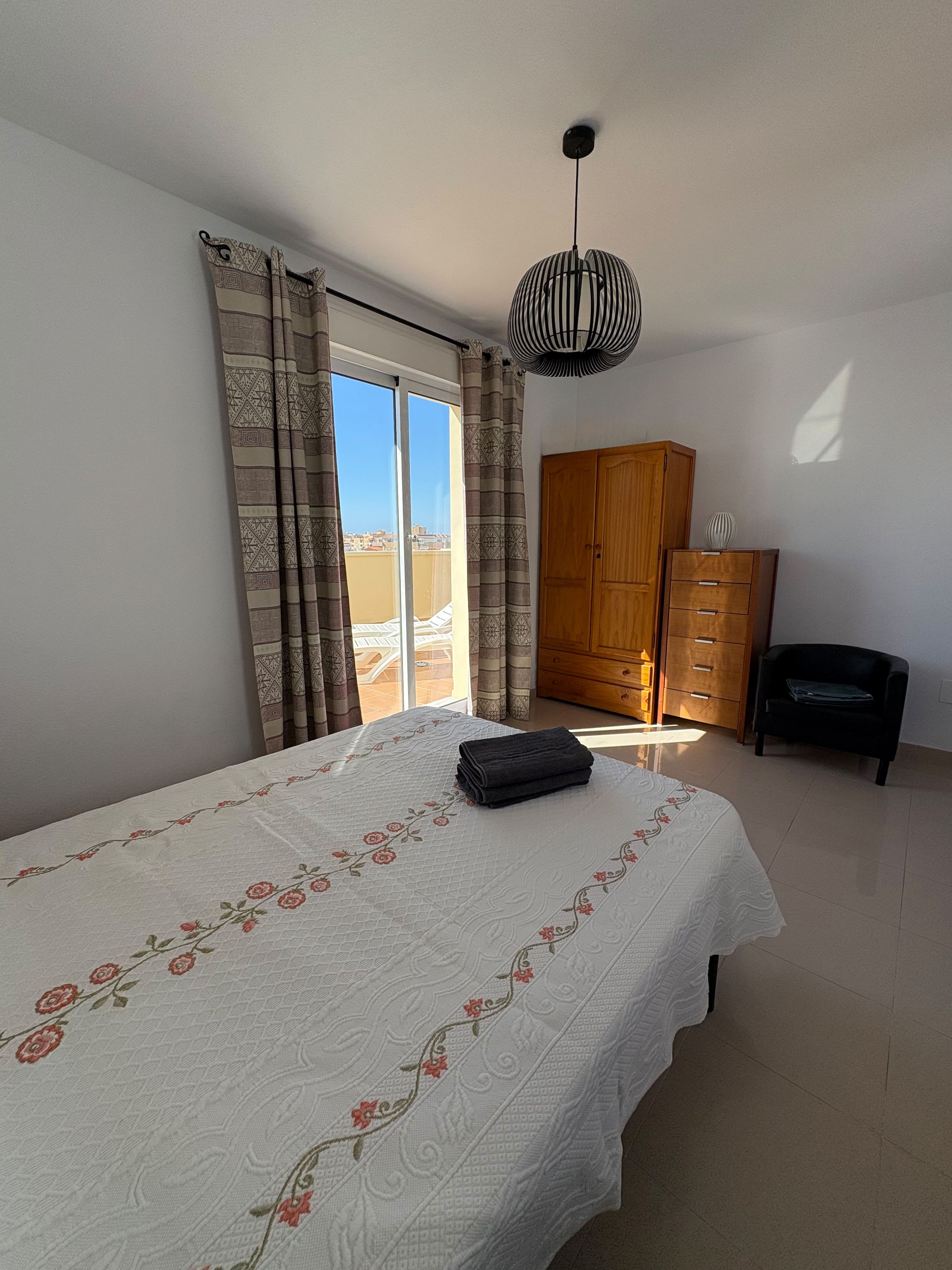 Une chambre à coucher avec un lit, une armoire, une chaise et une vue par la fenêtre.