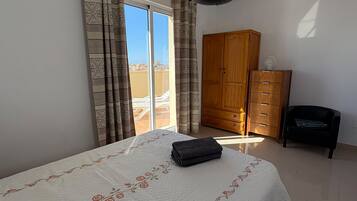 Une chambre à coucher avec un lit, une armoire, une chaise et une vue par la fenêtre.