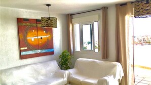 Un salon avec un canapé blanc, une petite table ronde et un tableau accroché au mur.