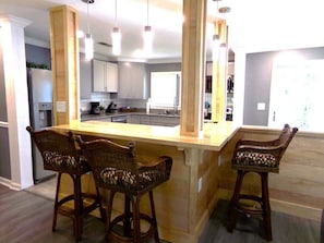 A kitchen with a central island, bar stools, and pendant lighting.