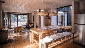 Un intérieur moderne en bois, comprenant une table à manger, des bancs et un coin cuisine.
