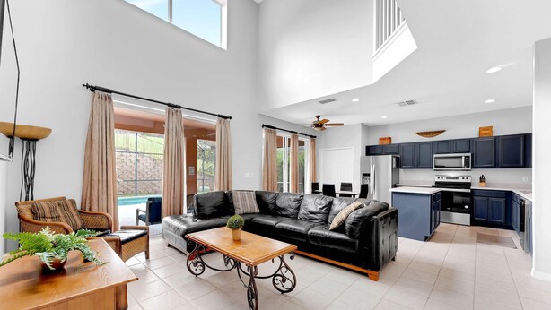 A spacious living room with a black leather sofa, a wooden coffee table, and a dining area. - Near Disney with Themed Rooms, Pool & Hot Tub (Kissimmee)