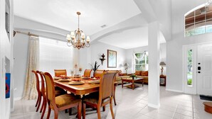 A spacious dining area with a large wooden table, multiple chairs, and a chandelier. - Near Disney with Themed Rooms, Pool & Hot Tub (Kissimmee)