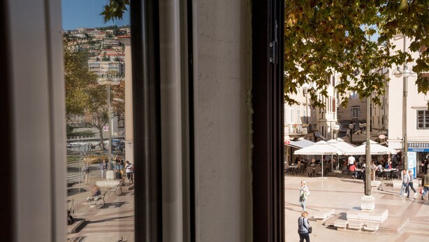 An outdoor urban plaza with seating areas, a fountain, and people walking. - City Life Rijeka (Rijeka)