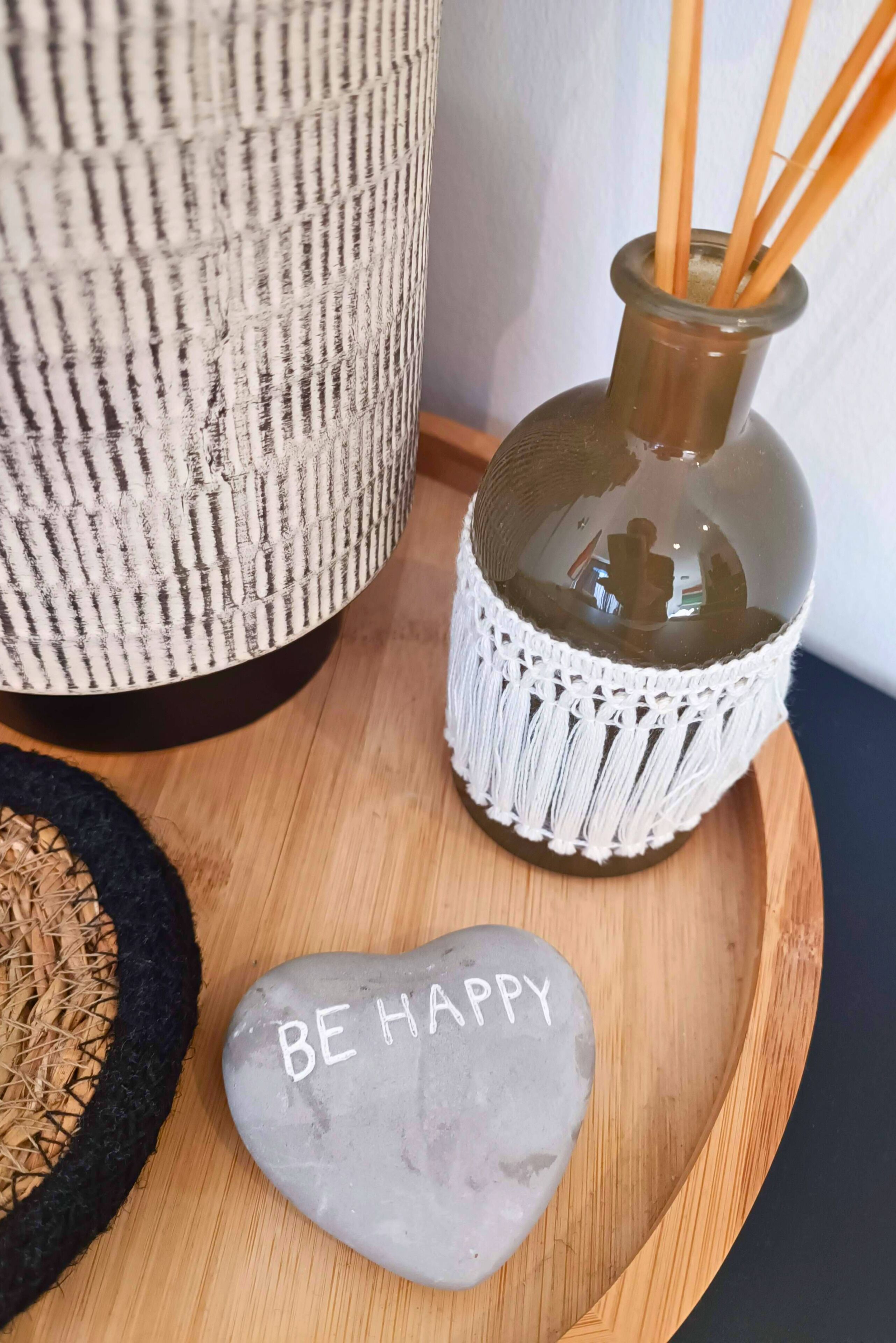 A decorative tray with a stone, a macrame vase, and a woven basket.