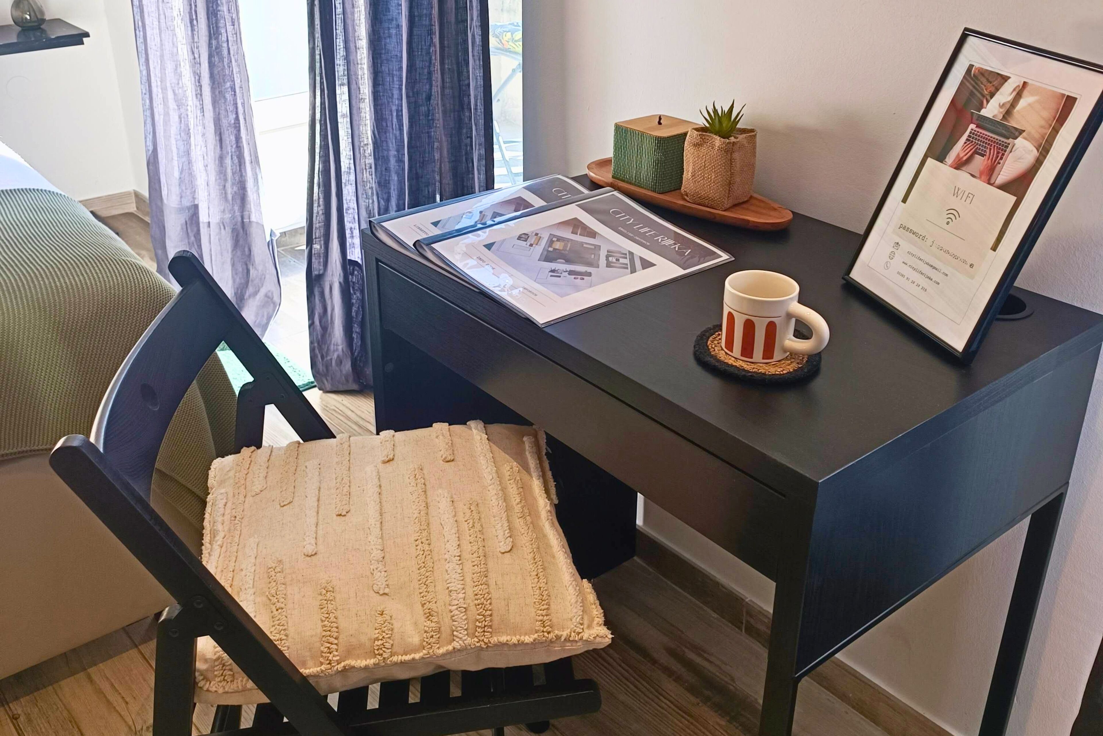 A modern office chair with a textured cushion, a desk with a framed picture, a mug, and a small plant on a tray.