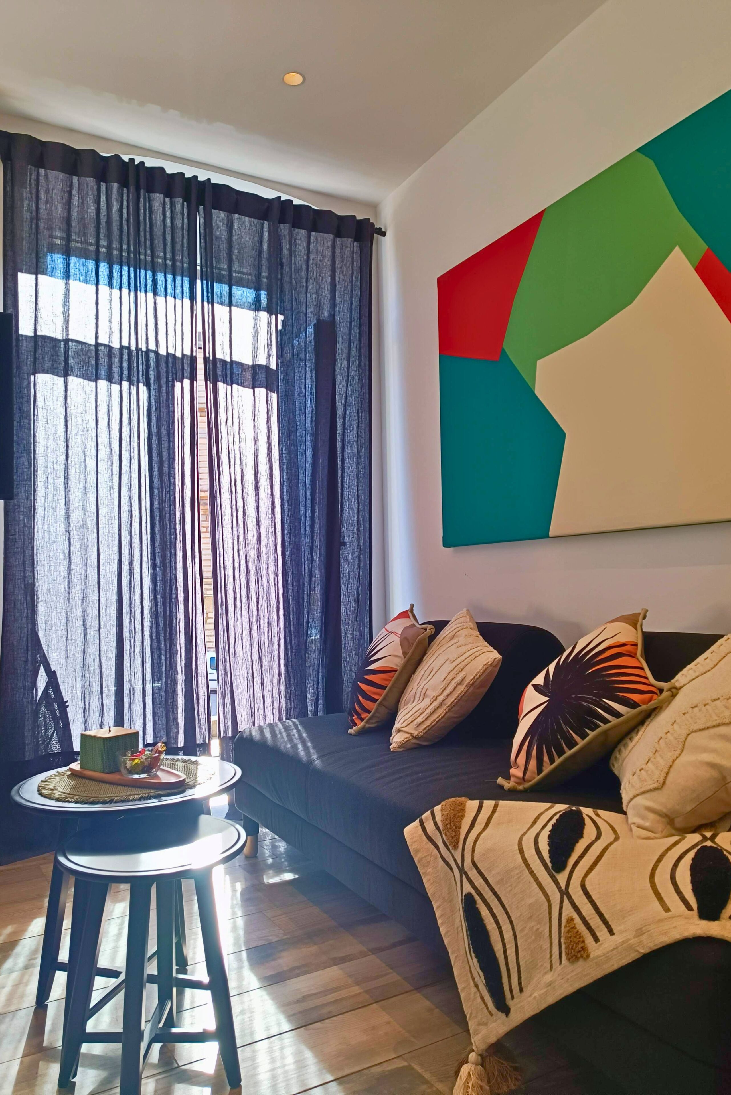 Una sala de estar con un sofá, una mesa redonda y un cuadro abstracto colgado en la pared.
