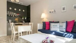 A modern living room with a white sofa, a coffee table, and a dining area with a white table and chairs. - Joanna's Apartment Warsaw Old Town Rycerska street (Warszawa)