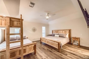 Une chambre avec un lit superposé, un lit simple, un ventilateur de plafond et une fenêtre.