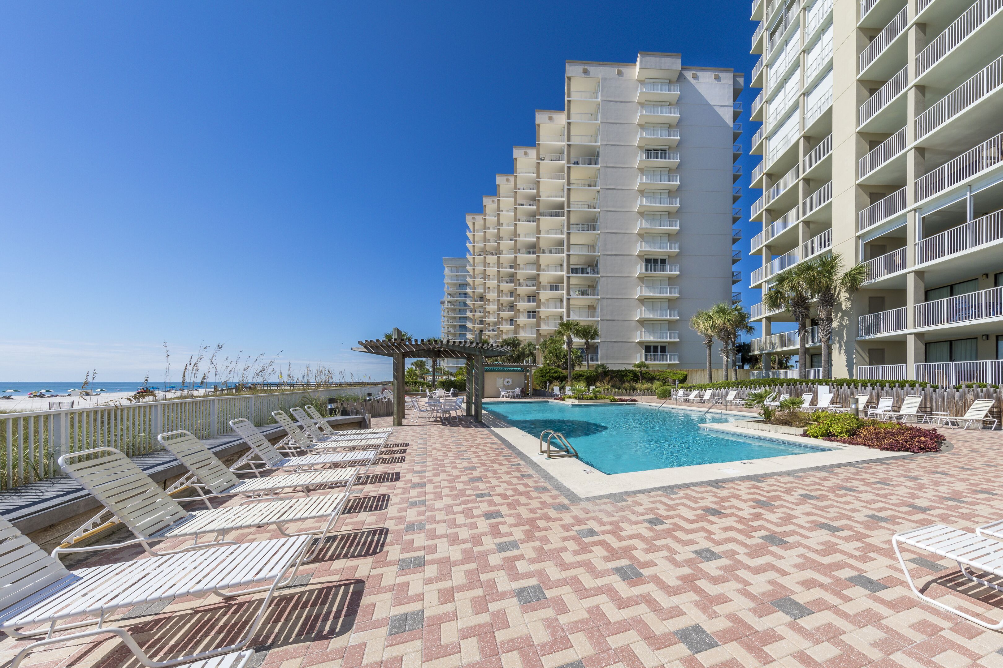 A hotel pool area with lounge chairs and a clear view of the ocean.