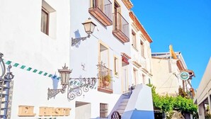 Un bâtiment blanc avec un escalier menant à un deuxième étage, une enseigne indiquant « EL RESIDENCI » et un lampadaire.
