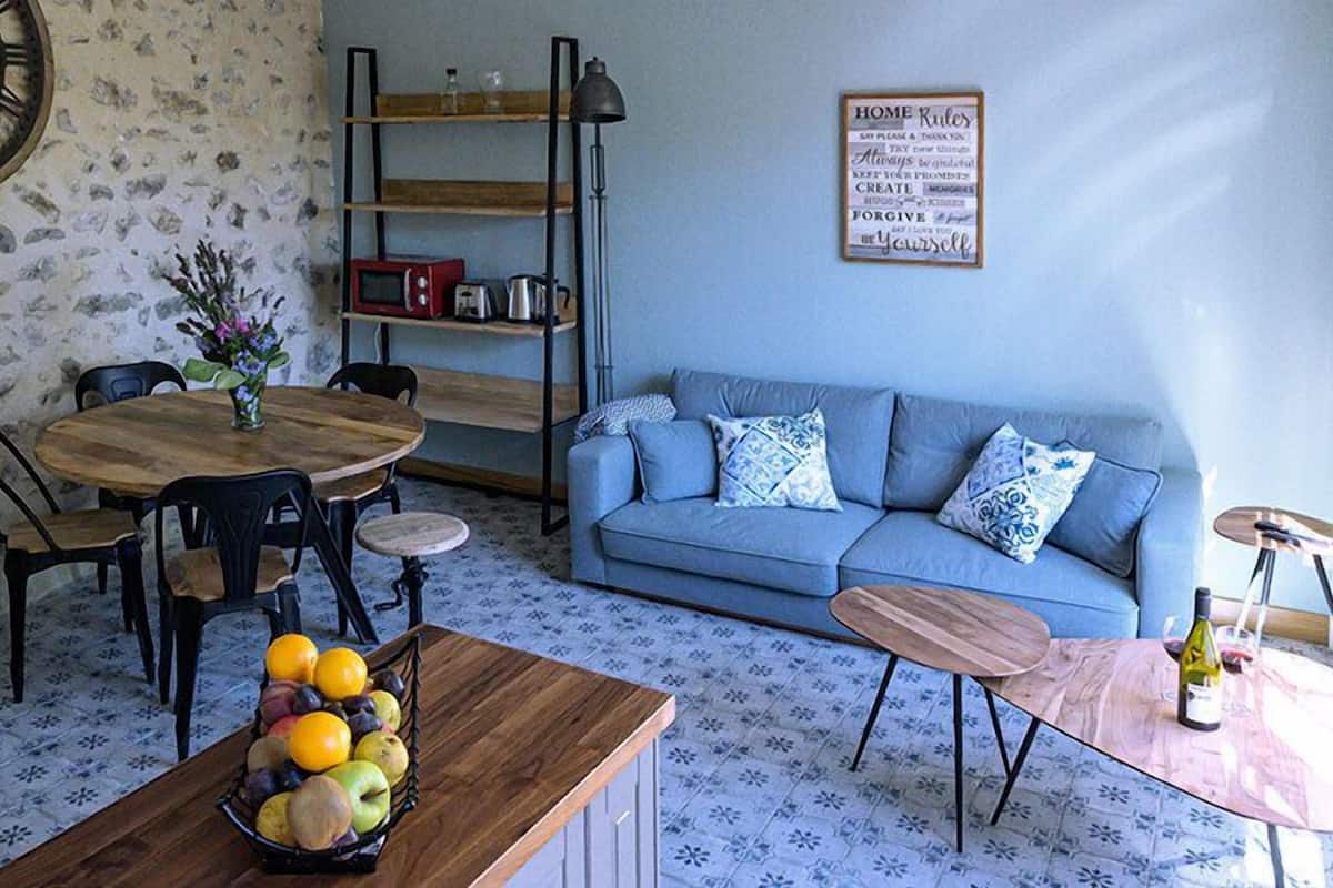 A cozy living room with a blue sofa, wooden coffee table, and a dining area with a wooden table and chairs.