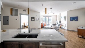A modern kitchen with a large island, built-in appliances, and pendant lighting.
