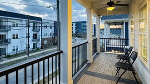 Une véranda couverte avec un ventilateur de plafond, une balustrade et deux chaises.