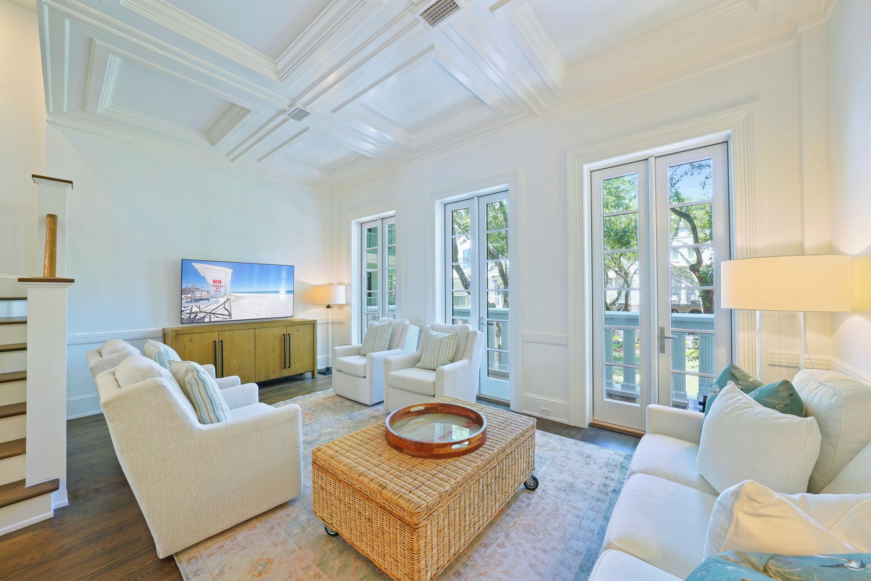 A spacious living room with a large window, a television, and a wicker coffee table.