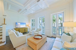 A spacious living room with a large window, a television, and a wicker coffee table.