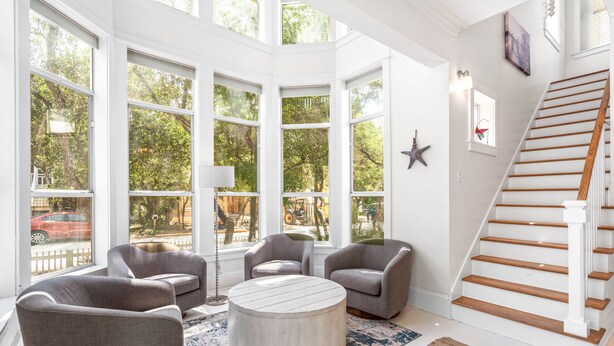 A spacious room with large windows, a round coffee table, and a staircase. - 1 Minute Stroll to Gulf with Private Heated Pool, Bikes, and a Gulf View (Santa Rosa Beach)