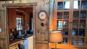 A rustic wooden interior with a kitchen area, a clock, and a lamp. - Cabin on Sunset Lake W/Boathouse 
Separate Bunkhouse Rental
PET FRIENDLY  (Orwell)