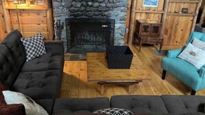 A cozy living room with a stone fireplace, wooden furniture, and a bookshelf. - Cabin on Sunset Lake W/Boathouse 
Separate Bunkhouse Rental
PET FRIENDLY  (Orwell)