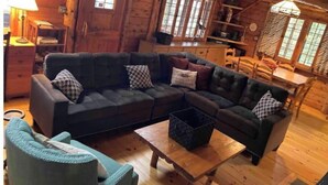 A cozy log cabin interior with a dark leather sofa, a wooden coffee table, and a blue armchair. - Cabin on Sunset Lake W/Boathouse 
Separate Bunkhouse Rental
PET FRIENDLY  (Orwell)