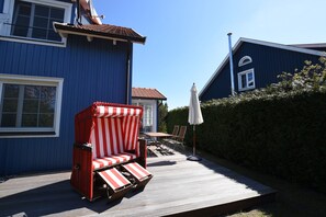 Eine Terrasse mit einem roten und weißen Streifenstuhl, einem Tisch und Stühlen.