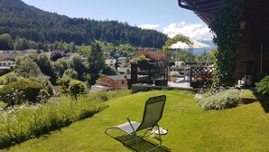 A garden with a lawn, a chair, and a view of a town and mountains in the background. - spacious apartment with nice view of the Tyrolean mountains (Reith bei Seefeld)