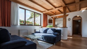 A modern living room with a blue sofa, a glass coffee table, and wooden beams on the ceiling. - spacious apartment with nice view of the Tyrolean mountains (Reith bei Seefeld)