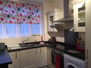 Compact kitchen with a washing machine and window.