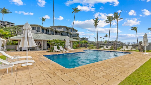 A swimming pool with lounge chairs and umbrellas, surrounded by palm trees and a clear sky. - Kapalua Bay Villa 12G5 By Parrish Maui - Private end unit (Kapalua)