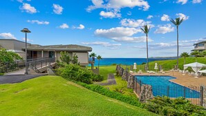 A residential property with a swimming pool, a covered patio area, and a view of the ocean.