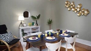 A dining area with a table set for four, surrounded by white chairs. A lamp and a shelf with decorative items are visible in the background. - Lisbon Liberdade Central Apartment 1E (Lisboa)