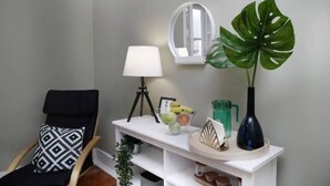 A corner of a room with a black chair, a white console table, a mirror, a lamp, and a large green plant. - Lisbon Liberdade Central Apartment 1E (Lisboa)