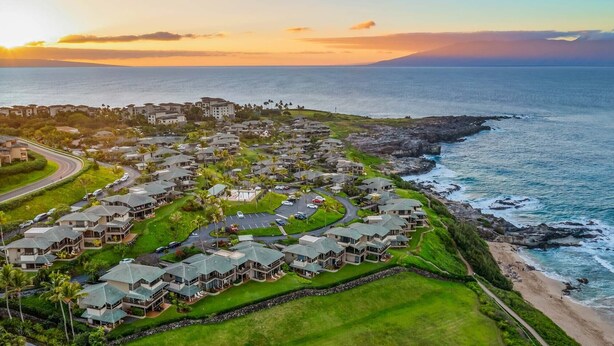 A coastal residential area with multiple-story houses, a road, and a beach.
