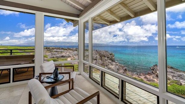 Een ruim balkon met vrij uitzicht op de oceaan en de rotsachtige kustlijn.