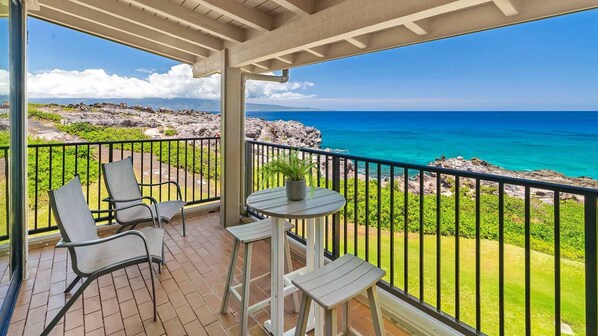 Ein Balkon mit Blick auf das Meer, einem Tisch mit Stühlen und einem Blumentopf.