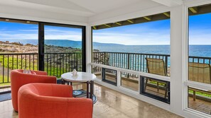 Un balcón con vista al mar, amueblado con una mesa y sillas.