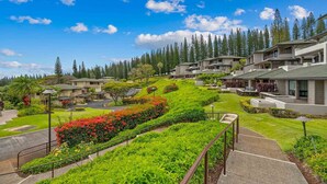 Un quartier résidentiel avec des maisons modernes, un jardin bien entretenu où s'épanouissent de magnifiques fleurs, et une vue dégagée sur la forêt environnante.