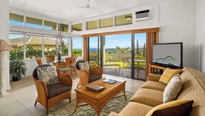 A spacious living room with a large TV, comfortable seating, and a view of the outdoors.