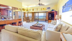 A spacious living area with a sofa, chairs, a coffee table, and a television.