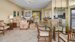 A spacious living room with a sofa, armchairs, and a glass dining table.