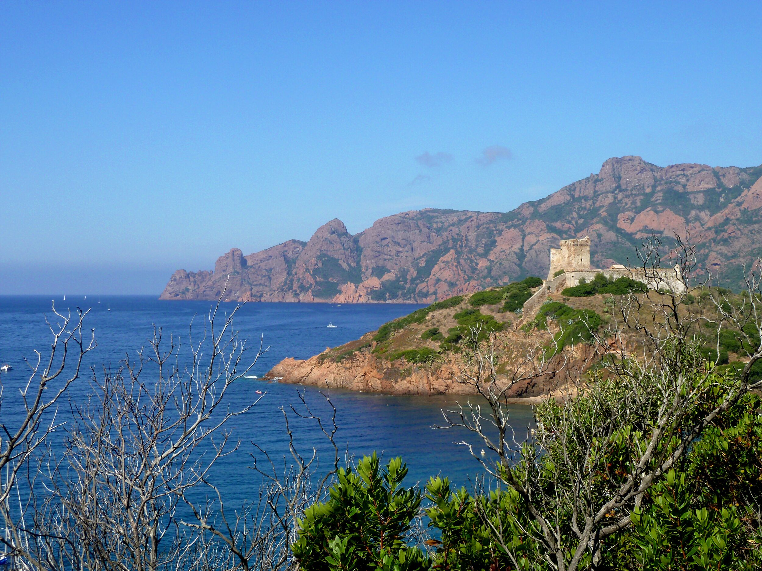 Un paisaje costero con una torre de piedra histórica en una colina, con vistas al mar.