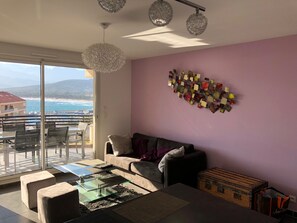 Enjoy breathtaking views of the sea and mountains from this spacious living area with a sliding glass door leading to a balcony and dining area.