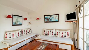 Ein modernes Wohnzimmer mit einer Sofagarnitur, einem Holztisch und einem an der Wand montierten Fernseher.