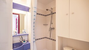 Ein Badezimmer mit Dusche, Toilette, Waschbecken und Spiegel.