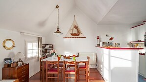 Ein Essbereich mit Holztisch und -stühlen, einer hängenden Leuchte und einer an der Wand befestigten Bootsdekoration.