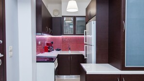 A modern kitchen with dark wooden cabinets, a white countertop, and a red-tiled backsplash. - Beautiful new decorated apt in Athens (Athens)