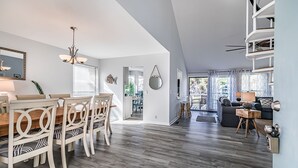 Ein großzügiger Wohnbereich mit Esstisch und Stühlen, einer Treppe und einem Balkon mit Blick.