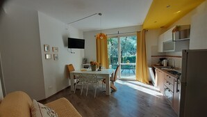Un appartement moderne comprenant un coin repas, une cuisine et un canapé recouvert d’une housse matelassée.