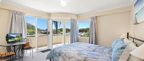 A hotel room with a bed, a TV, a balcony, and a view of the outdoors.